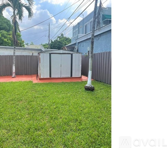 A small white refrigerator is in the middle of a grassy yard.