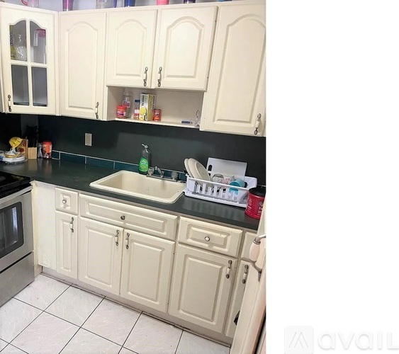 A kitchen with white cabinets and a black countertop.