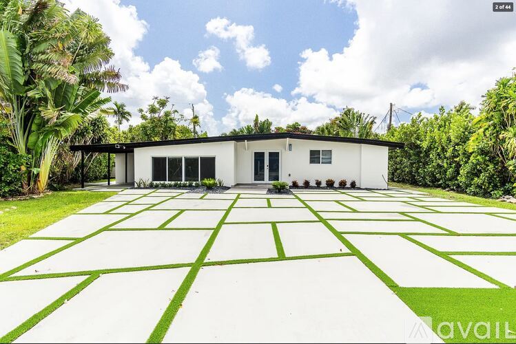 A white house with a black roof and a green lawn in front.
