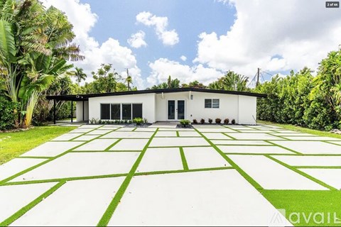 A white house with a black roof and a green lawn in front.