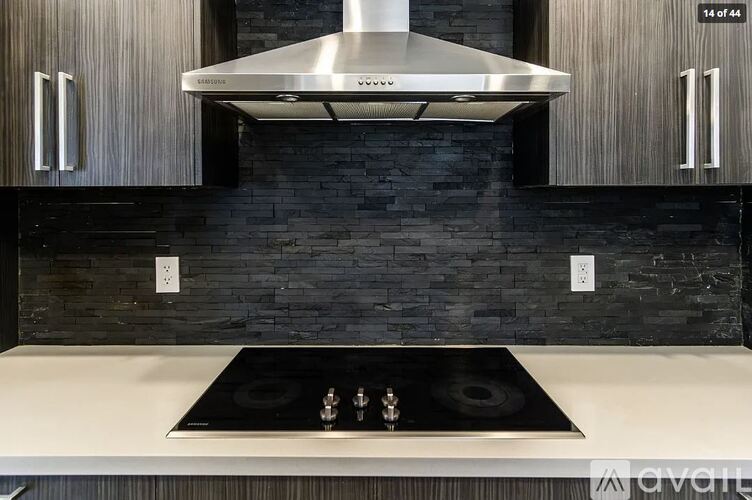 A modern kitchen with a stove top oven and a hood above it.