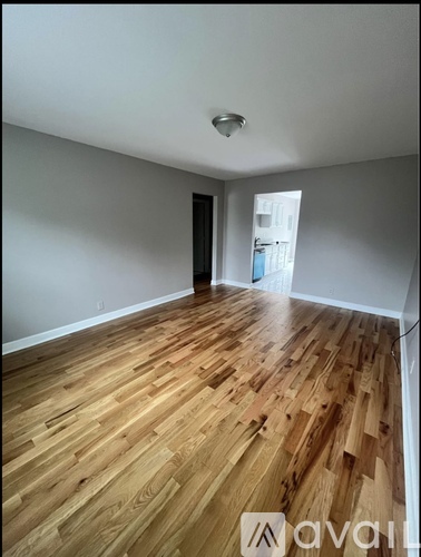 A room with wooden flooring and a door on the left side.