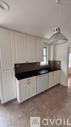 A kitchen with white cabinets and a black countertop.