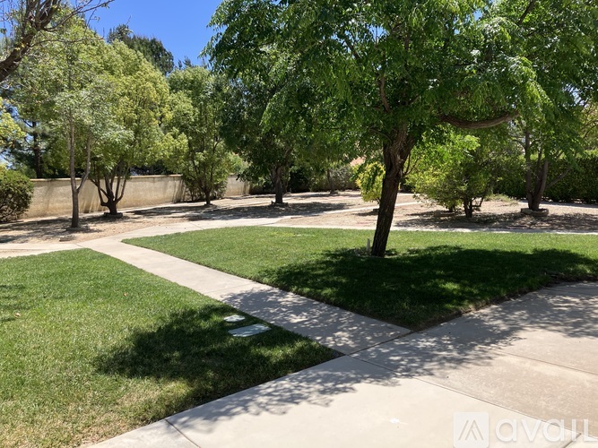 A park with a concrete walkway and green grass.