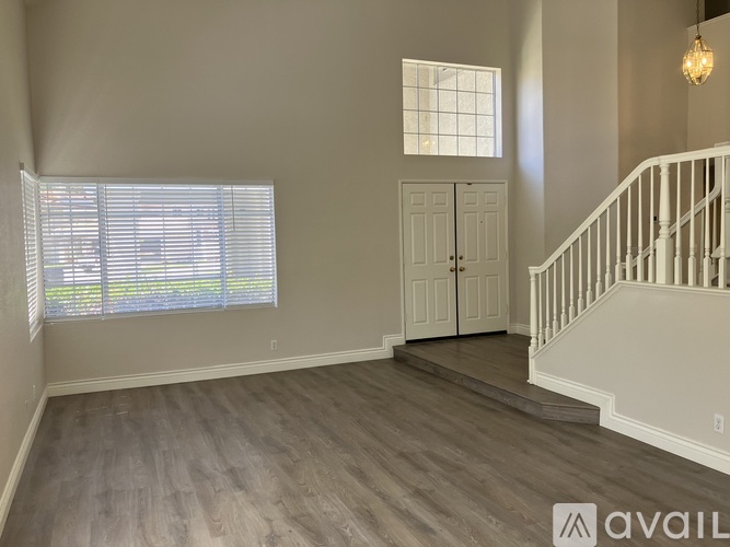A spacious room with a staircase and a window with blinds.
