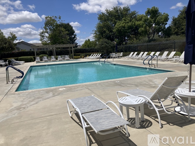 A pool with sun loungers and a black umbrella.