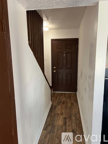 A hallway with a wooden door and steps leading up to it.