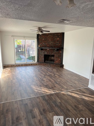 A room with a fireplace and wood flooring.
