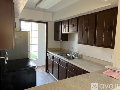 A kitchen with brown cabinets and a black fridge.