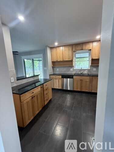 A kitchen with wooden cabinets and black tiled flooring.
