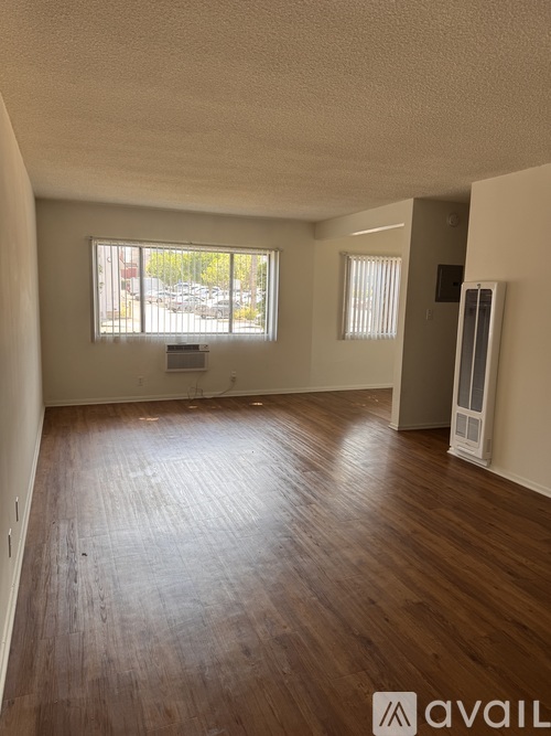 A room with wooden floors and a window overlooking a parking lot.