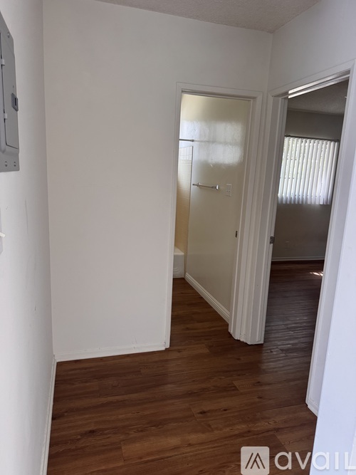 A room with a white door and wooden flooring.