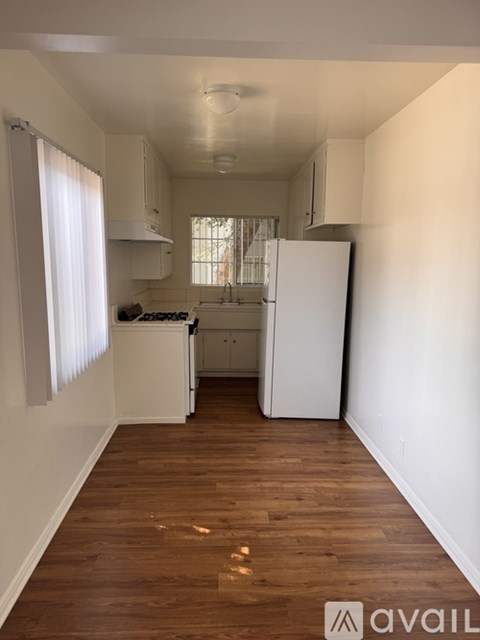A kitchen with white appliances and wooden floors.