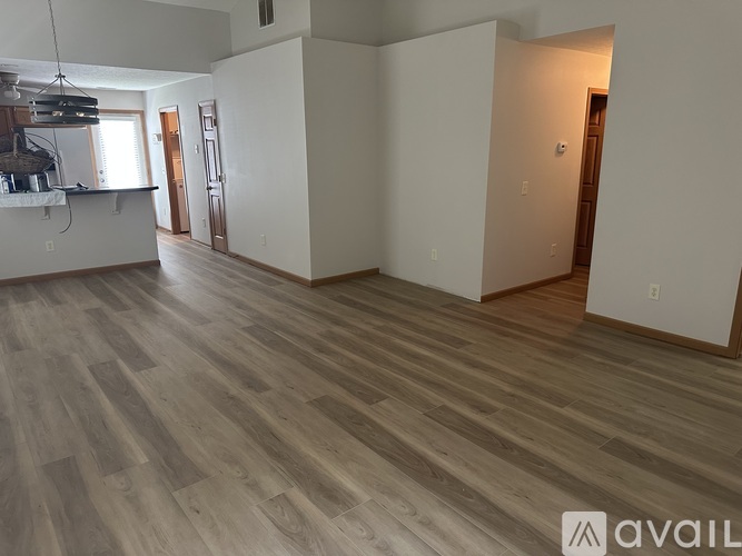 A spacious room with wooden flooring and white walls.