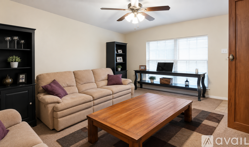 A living room with a brown sofa, a wooden table, and a ceiling fan.
