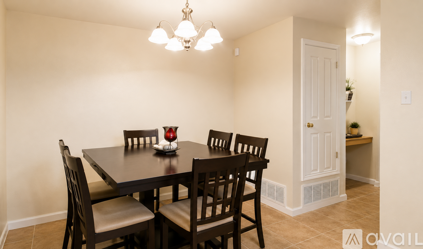 A dining room with a table set for two and chairs around it.