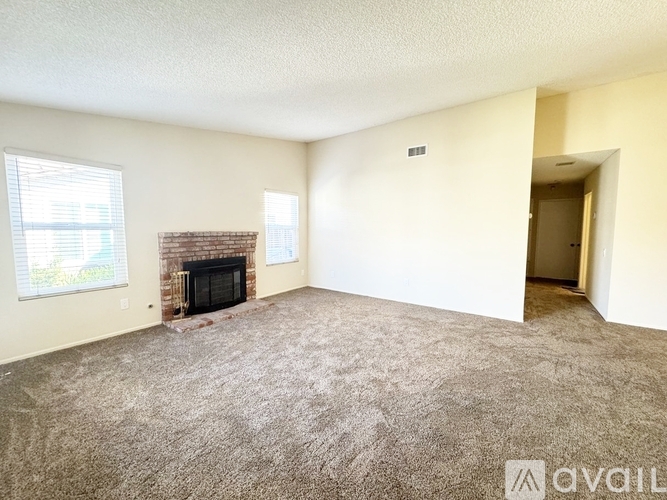 A living room with a fireplace and carpeted floor.