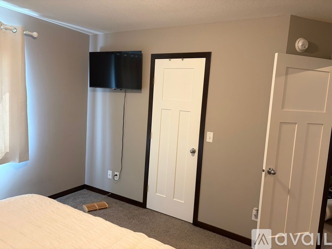 A bedroom with a bed, a television, and three doors.