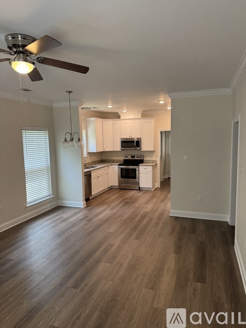 A kitchen with a fan and wooden floors.