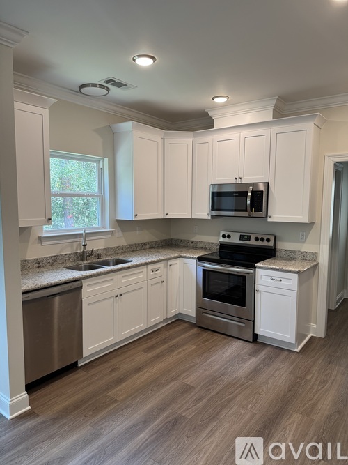 A kitchen with white cabinets and a wooden floor.