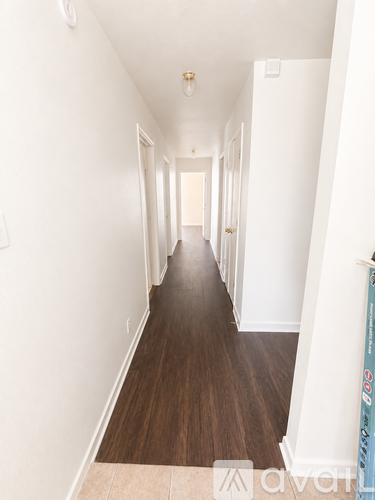 A long hallway with wood floors and white walls.