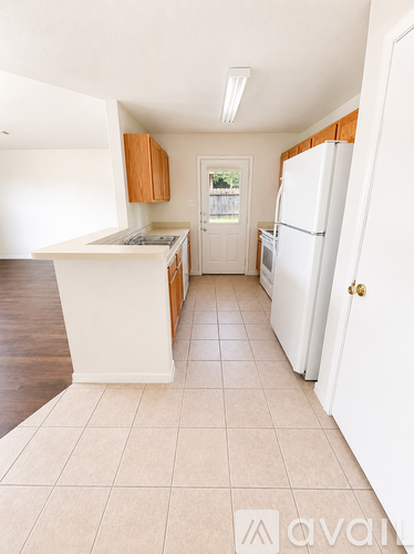 A kitchen with white appliances and wooden cabinets.