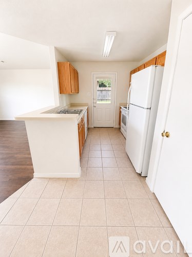 A kitchen with white appliances and wooden cabinets.