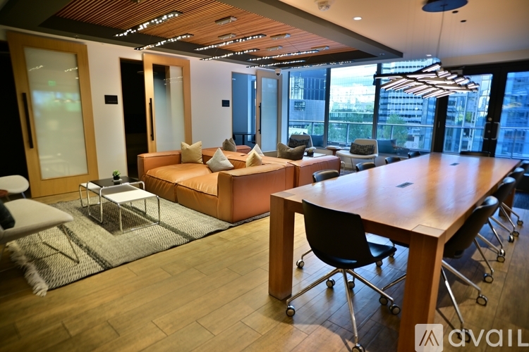 A modern office space with a long table and chairs, a couch, and a view of the city.