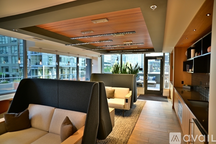 A modern living room with a black sofa and a wooden ceiling.