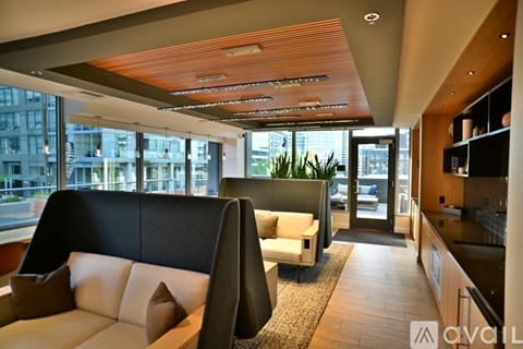 A modern living room with a black sofa and a wooden ceiling.