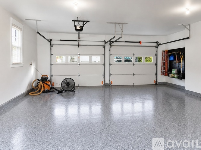 A spacious garage with a fan and a hose on the floor.