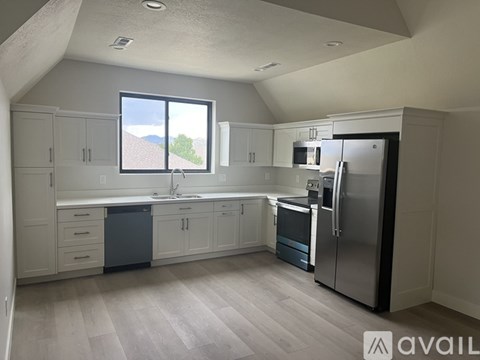 A kitchen with a refrigerator, sink, and cabinets.