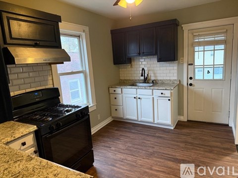 A kitchen with dark wood cabinets and a black stove top oven.