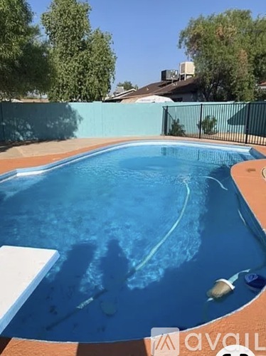 A small pool with a white fence and trees in the background.