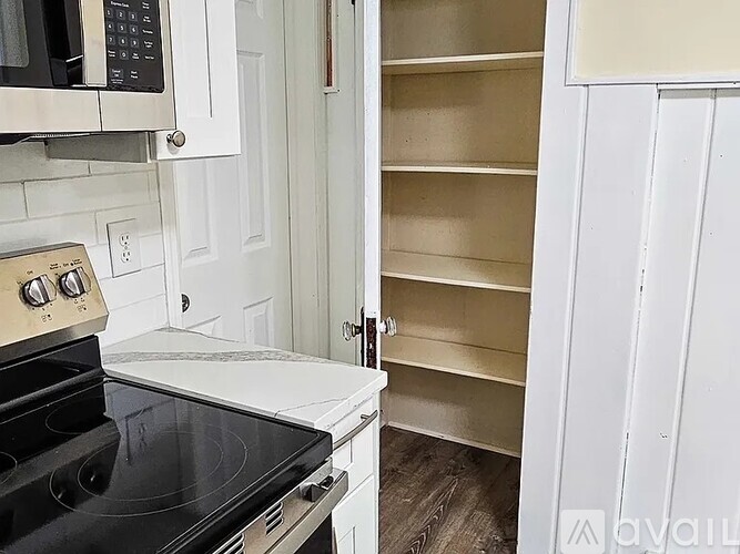 A kitchen with a black stove top oven and white cabinets.