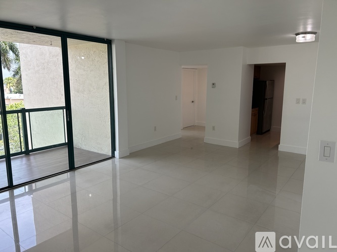 A spacious room with a sliding glass door and a white door.