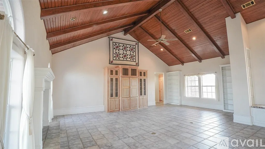 A spacious room with a wooden ceiling and tiled floor.