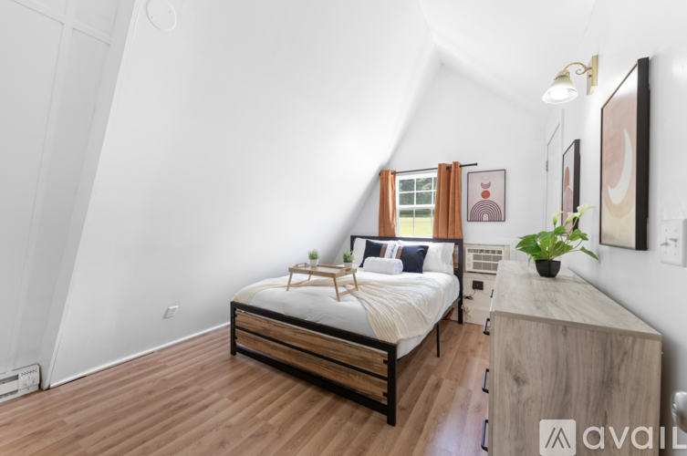 A bedroom with a bed, nightstand, and a plant.