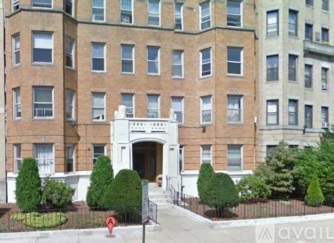 A tall brick building with a white entrance and a black fence.