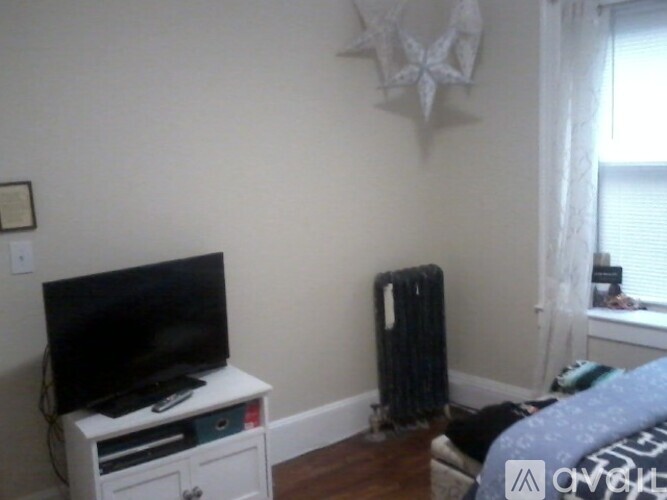 A black television sits on a white stand in a room with a wooden floor.