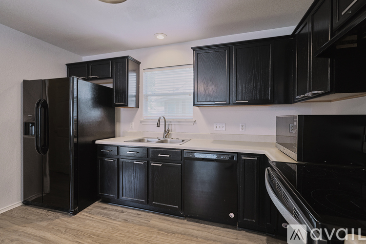 A kitchen with black cabinets and appliances.