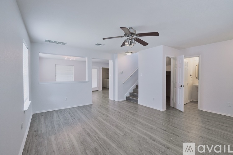 A spacious room with a ceiling fan and wooden flooring.