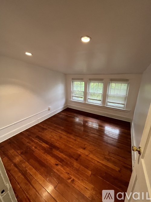 A room with wooden flooring and a window with blinds.