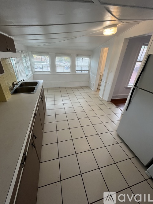A kitchen with white appliances and white tiled floors.