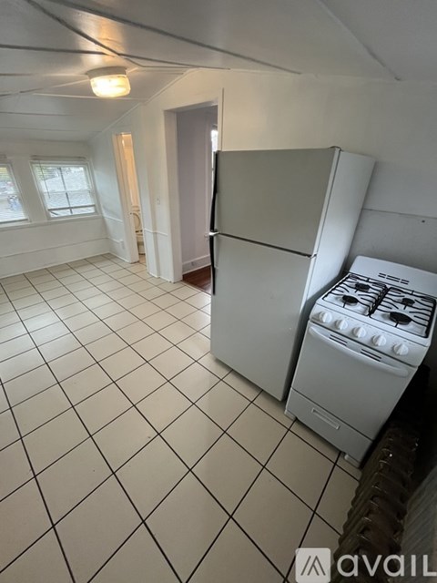 A white kitchen with a stove and a refrigerator.