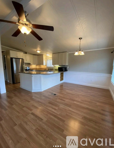 A kitchen with a fan and wooden flooring.
