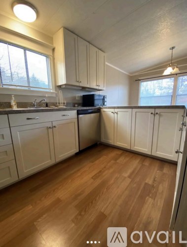 A kitchen with white cabinets and wooden floors.