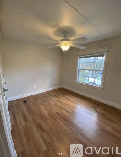 A room with a ceiling fan and wooden flooring.