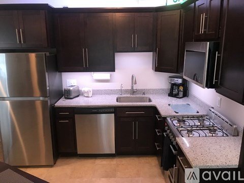 A kitchen with dark brown cabinets and a stainless steel refrigerator.