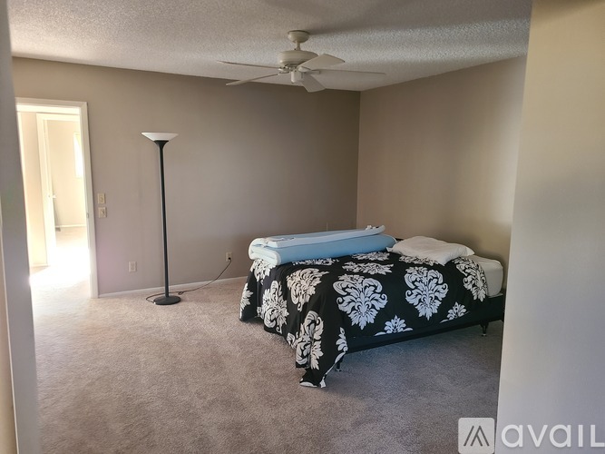 A bedroom with a bed, lamp, and carpet.